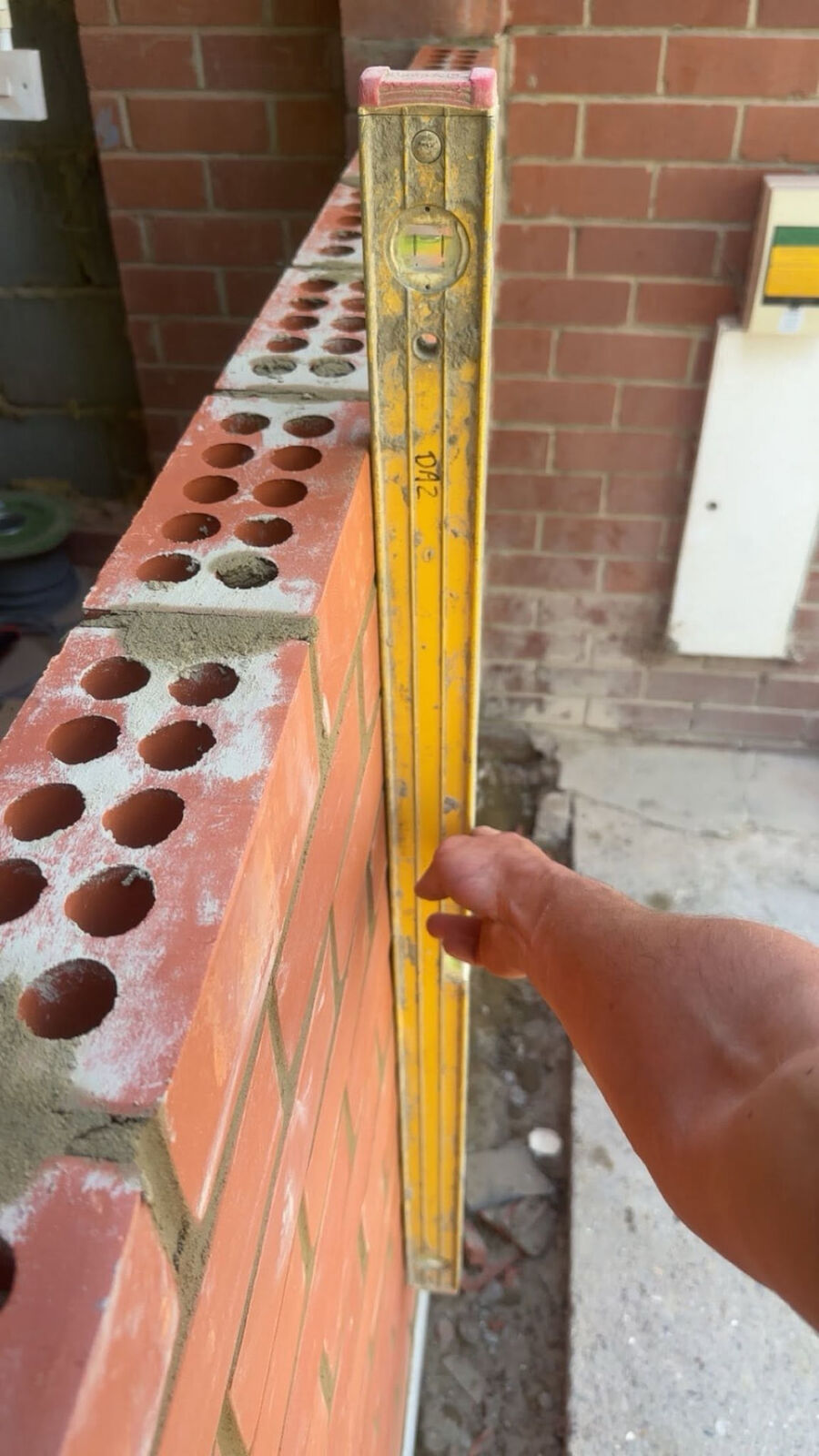 Spirit level checking a brick wall is true