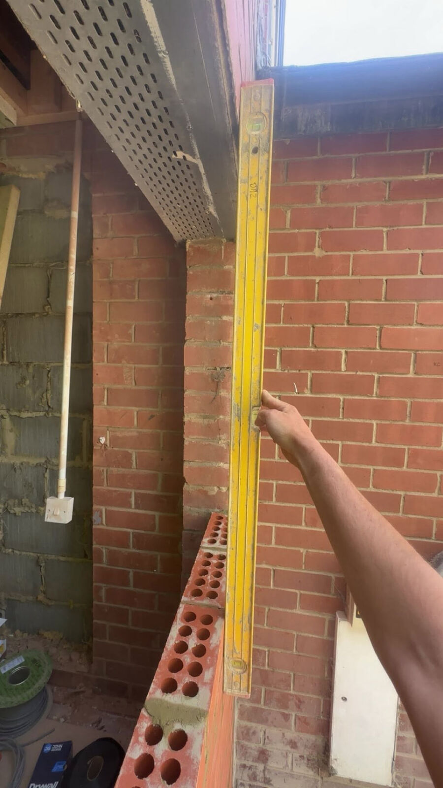 Bricklayer checking a wall is plumb with a spirit level