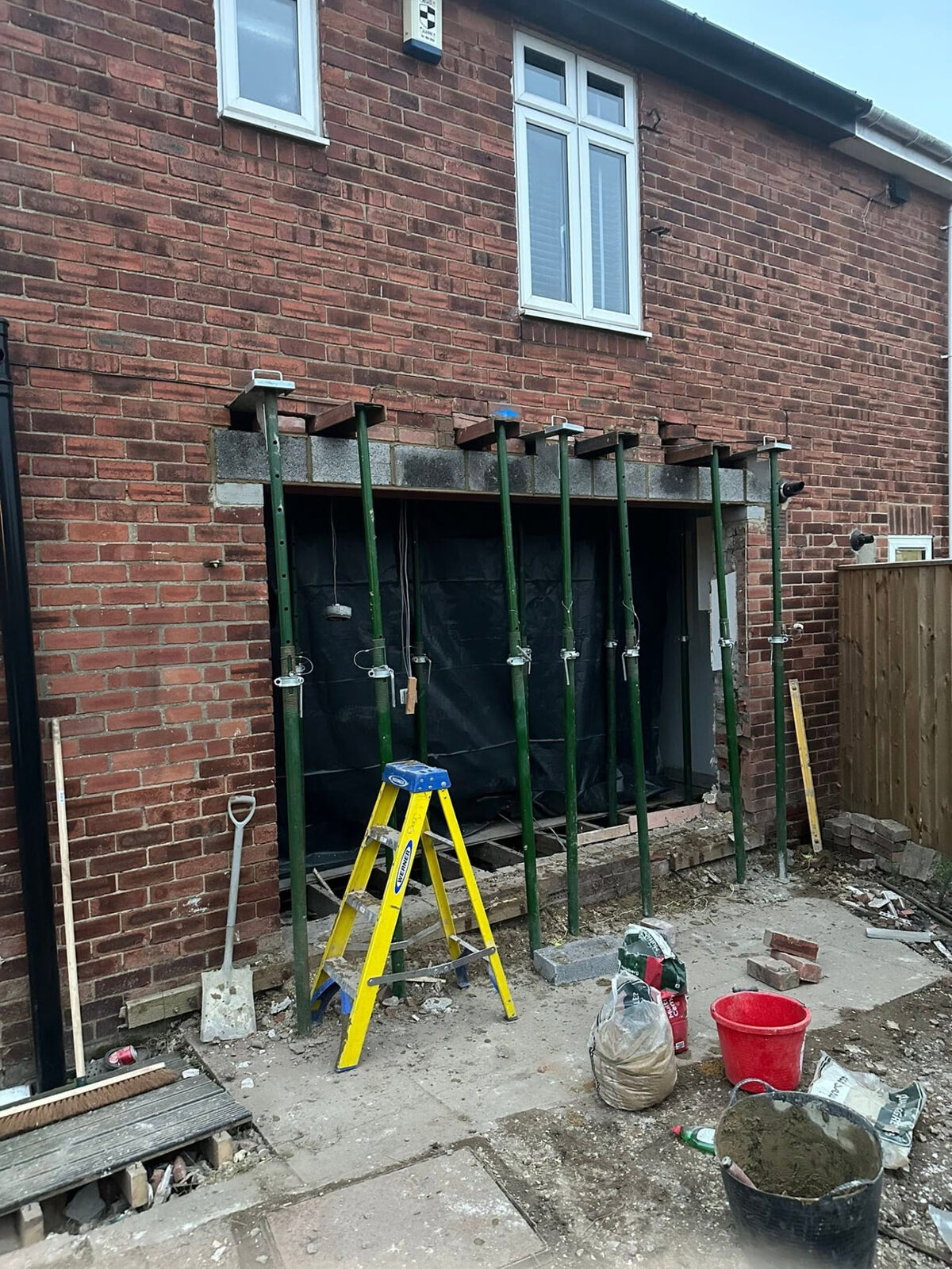 Large new opening in a rear brick wall supported by props during alteration work