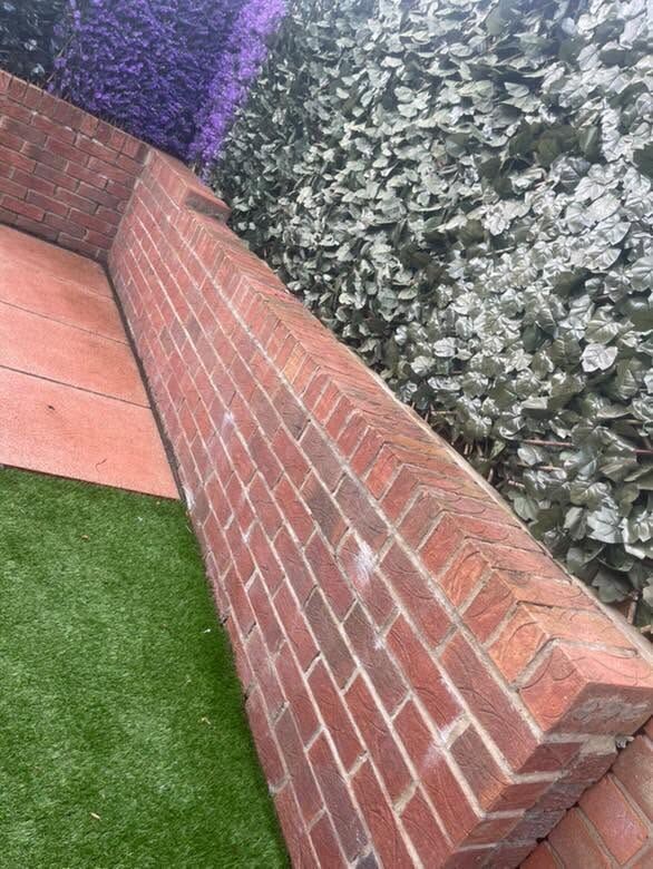 Curved red-brick garden wall beside an artificial lawn